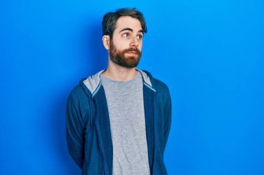 Sakallı, sıradan bir kazak giyen beyaz bir adam gülümseyip yan tarafa bakıyor ve düşünüyor.. 