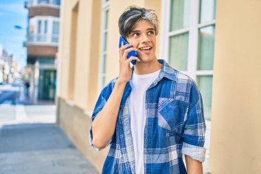 Genç İspanyol adam gülümsüyor. Şehirdeki akıllı telefondan konuşuyor..