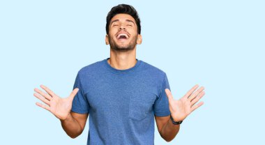 Gündelik kıyafetler giyen genç, çılgın ve çılgın başarıyı kutlayan kollarını kaldırmış, gözlerini kapatmış heyecanlı çığlıklar atan yakışıklı bir adam. Kazanan konsept 