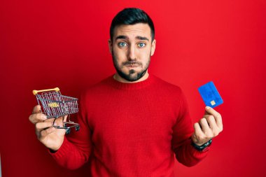 Genç İspanyol adam elinde küçük bir süpermarket arabası ve komik suratlı kredi kartı şişiren yanaklar tutuyor. Ağzı havayla şişer, havayı yakalar.. 