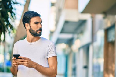 Şehirde akıllı telefon kullanan ciddi bir suratı olan genç bir İspanyol..