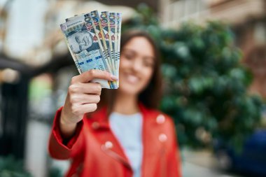 Genç İspanyol kadın gülümsüyor. Mutlu bir şekilde Peru banknotlarını şehirde tutuyor..