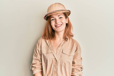 Yüzünde mutlu ve havalı bir gülümseme olan kaşif şapkası takan beyaz bir kadın. şanslı kişi. 