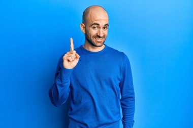 Sıradan bir kazak giyen genç İspanyol bir adam bir fikir veya soruyla gülümsüyor ve mutlu bir yüzle işaret ediyor. 