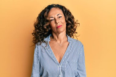 Orta yaşlı İspanyol kadın günlük kıyafetler giyiyor ve yüzünde ciddi bir ifadeyle rahatlıyor. Basit ve doğal bir şekilde kameraya bakıyorsun.. 