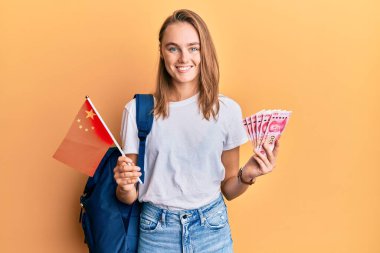 Güzel sarışın değişim öğrencisi elinde Çin bayrağı ve mutlu ve havalı bir gülümsemeyle gülümseyen Yuan banknotları tutuyordu. diş gösterme. 