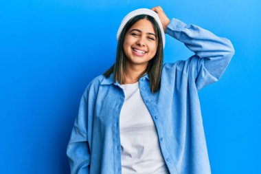 Şirin yün şapka takan, kendine güvenen, el hareketleriyle saçlara dokunan çekici ve modaya uygun poz veren genç Latin kadın. 