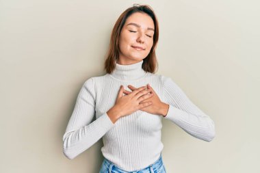 Gündelik kıyafetler giyen, göğsünde elleri, yüzünde minnet dolu bir jest ile gülümseyen beyaz bir kadın. sağlık kavramı. 