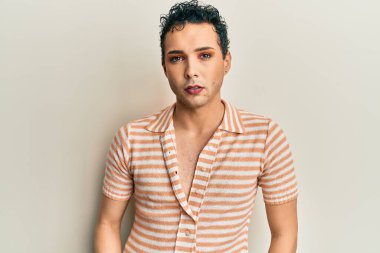 Makyaj gömleği giyen yakışıklı bir adam bir fikre ya da soru işaretine şaşırmış ve mutlu bir yüzle işaret ediyor. 