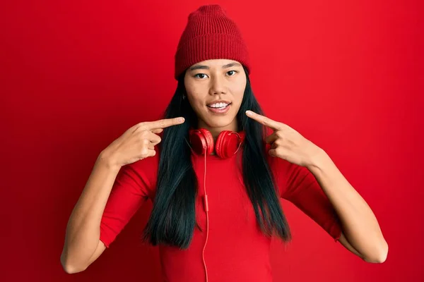 Mladá Číňanka Která Poslouchá Hudbu Pomocí Sluchátek Vesele Usmívá Ukazuje — Stock fotografie