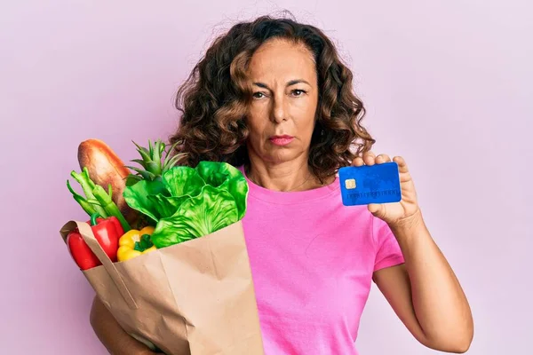 Mujer Hispana Mediana Edad Sosteniendo Comestibles Tarjetas Crédito Escéptico Nervioso —  Fotos de Stock