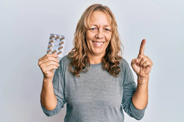 Middle Age Blonde Woman Holding Pills Smiling Idea Question Pointing — Stock Fotó