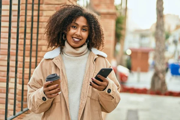 アフリカ系アメリカ人の若い女性が市内でスマートフォンやコーヒーを飲んでいる — ストック写真