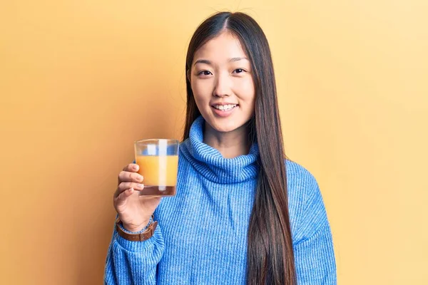 Νεαρή Όμορφη Κινέζα Γυναίκα Πίνει Ένα Ποτήρι Χυμό Πορτοκαλιού Δείχνοντας — Φωτογραφία Αρχείου