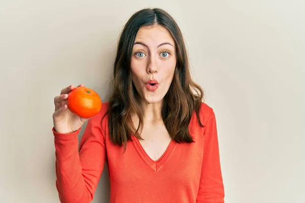 Ung Brunett Kvinna Håller Färsk Apelsin Rädd Och Förvånad Med — Stockfoto