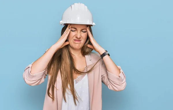 年轻的金发女人戴着建筑师的硬礼帽 由于疼痛和偏头痛 绝望和紧张 手放在头上 — 图库照片