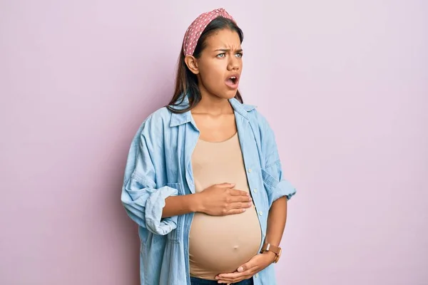 赤ちゃんを期待している美しいヒスパニック系の女性は 妊娠中の腹に触れて怒っていると怒りを叫び 怒りで叫んでいる 怒りと攻撃的な考え方 — ストック写真