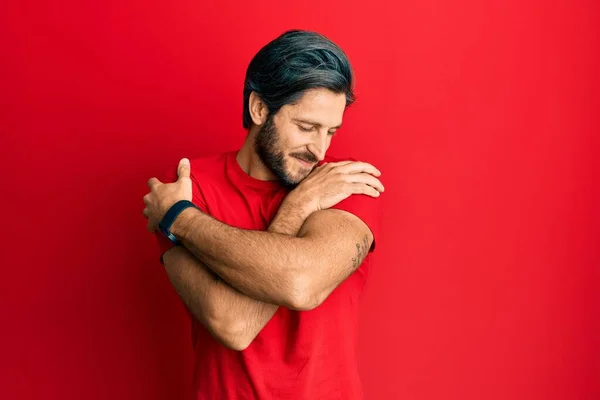 Young Hispanic Man Wearing Casual Red Shirt Hugging Oneself Happy — Stockfoto