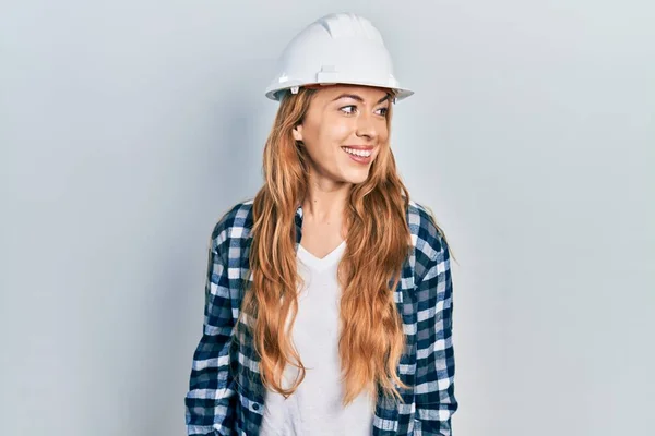 年轻的高加索女人头戴建筑师的硬礼帽 面带微笑 神态自然地望向一边 充满自信地大笑 — 图库照片