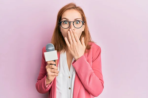 Young Caucasian Woman Holding Reporter Microphone Covering Mouth Hand Shocked — Stock Photo, Image