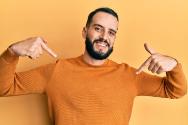 Sakallı genç adam, sıradan bir kazak giyiyor. Kendine güvenen, gülümseyen, kendini gururlu ve mutlu gösteren biri.. 