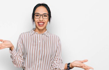 Gündelik kıyafetler ve gözlük takan genç İspanyol kız güler yüzlü kollar açık, dostça karşılama, olumlu ve kendinden emin selamlar. 