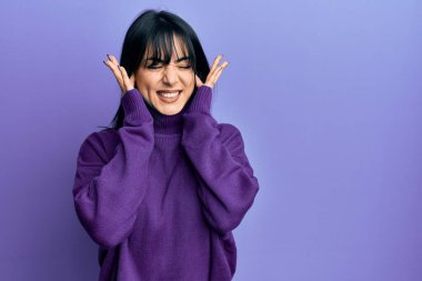 Kahküllü, balıkçı yaka kazak giyen genç esmer kadın yüksek sesli müzik sesi için kulaklarını parmaklarıyla kapatıyor. sağır kavramı. 