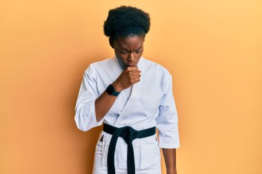 Karate kimonosu ve siyah kuşak giyen genç Afro-Amerikalı kız kendini kötü hissediyor ve soğuk algınlığı veya bronşitin belirtisi olarak öksürüyor. sağlık hizmeti kavramı. 