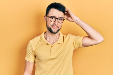 Gündelik kıyafet ve gözlük takan genç İspanyol adam soru sorup kafasını karıştırıyor. Şüpheyle kararsız, kafa kafaya düşünerek. Düşünceli kavram. 