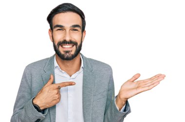 İş kıyafetleri giyen genç İspanyol adam kameraya hayret ediyor ve gülümsüyor.. 