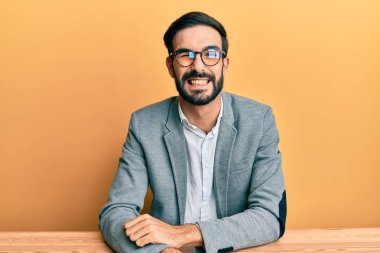 Ofiste çalışan genç İspanyol bir adam kameraya seksi bir ifadeyle bakıyor, neşeli ve mutlu bir yüzle.. 