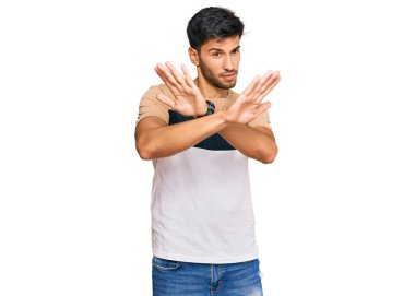 Genç, yakışıklı, sıradan kıyafetler giyen, reddedilmiş, kollarını kavuşturmuş, avuç içleri negatif işaretler veren, kızgın yüzlü bir adam. 