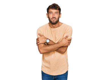 Sakallı yakışıklı genç adam, sıradan bir tişört giyiyor. Kış soğuğu için titriyor ve donuyor. Yüzünde üzgün ve şok ifadesi var. 