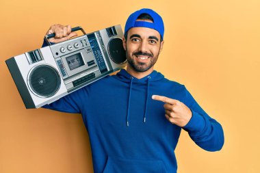 Kasetçalar tutan genç İspanyol adam, müzik dinliyor, gülümsüyor, mutlu bir şekilde işaret ediyor. 