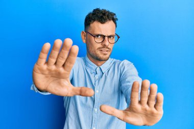 Günlük kıyafetler ve gözlük takan genç İspanyol adam avuçlarıyla jestleri durduruyor, kızgın ve hayal kırıklığına uğramış ifade ediyor. 