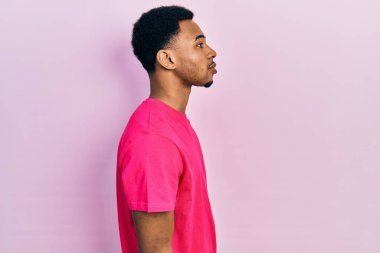 Casua tişörtü giyen genç Afro-Amerikan bir adam. Tişörtünü yana çevirmiş, rahat bir görünüm sergiliyor.. 