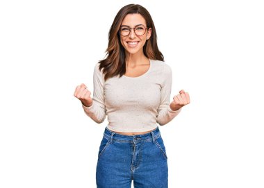 Gündelik kıyafetler ve gözlük takan genç esmer kadın başarının heyecanı içinde kollarını kaldırmış ve gözleri kapalı zaferi kutluyor. Kazanan konsept. 