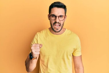 Gündelik kıyafetler giyen, gözlüklü, kızgın, kızgın, sinirli ve öfkeliyken öfkeyle bağıran genç bir İspanyol. öfke ve agresif konsept. 