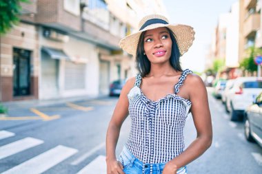 Genç Afro-Amerikan kadın tatilde gülümsüyor ve şehrin sokaklarında mutlu bir şekilde yürüyor.