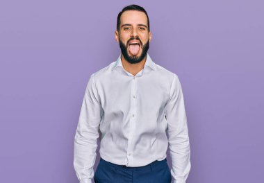 Sakallı, iş gömleği giyen, dilini komik bir ifadeyle dışarı çıkaran genç bir adam. duygu kavramı. 