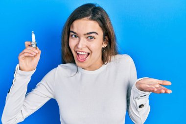 Genç beyaz kız elinde bujiyle başarıyı mutlu bir gülümsemeyle kutluyor ve kazanan el kaldırarak ifade ediyor. 