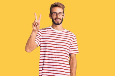 Sakallı, sıradan kıyafetler giyen, gözlüklü yakışıklı bir adam. İki numaralı parmaklarıyla onu gösteriyor ve gülümsüyor. Kendinden emin ve mutlu.. 