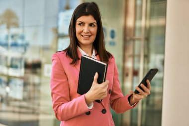 Emlakçı olarak çalışan orta yaşlı bir iş kadını. Akıllı telefon kullanan satıcı kadın.