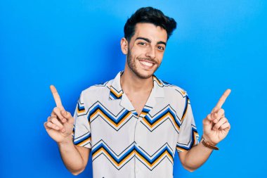 Gündelik kıyafetler giyen, kendine güvenen, parmaklarını farklı yönlere çeviren genç İspanyol adam. reklam için kopyalama alanı 