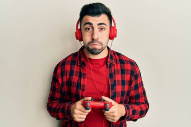 İspanyol asıllı genç adam video oyunu oynuyor, elinde kontrolör, komik suratıyla yanaklarını şişiriyor. Ağzı havayla şişer, havayı yakalar.. 