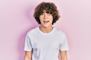 Yakışıklı, beyaz tişört giyen, kameraya seksi bir ifadeyle, neşeli ve mutlu bir yüzle bakan genç adam.. 