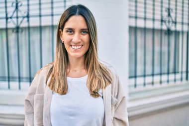 Genç beyaz kadın gülümseyerek şehirde mutlu mesut yürüyor..