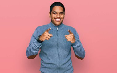 Sıradan bir kazak giyen genç, yakışıklı İspanyol adam mutlu ve komik yüzlü parmaklarını kameraya doğrultuyor. iyi enerji ve titreşimler. 