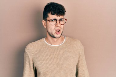 Şok olmuş gözlüklü, sıradan kıyafetler giyen genç İspanyol adam şüpheci ve alaycı görünüyor, ağzı açık kalınca şaşırıyor. 