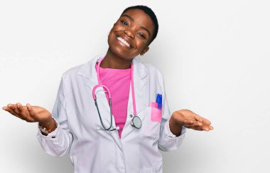 Genç Afro-Amerikan kadın doktor üniforması giyiyor ve steteskop 'un hiçbir şeyden haberi yok ve elleri ve kolları havada kafası karışık bir ifade takınıyor. şüphe kavramı. 